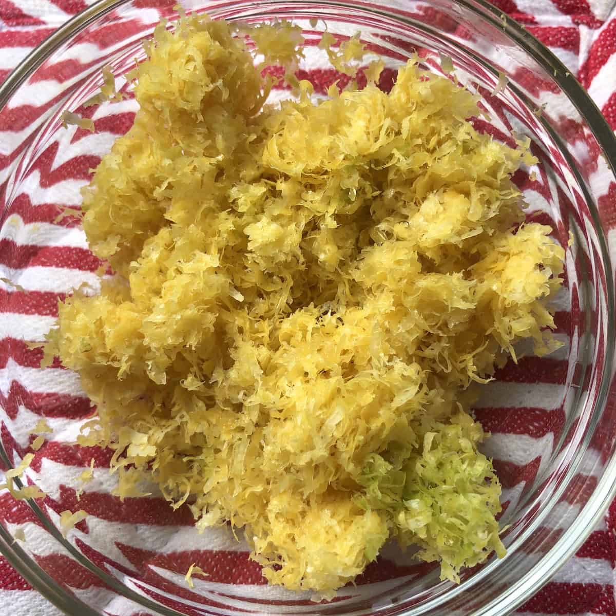 A glass bowl full of fresh lemon zest for making homemade limoncello, peeled lemon zest is the key limoncello ingredient for an authentic Italian limoncello recipe.
