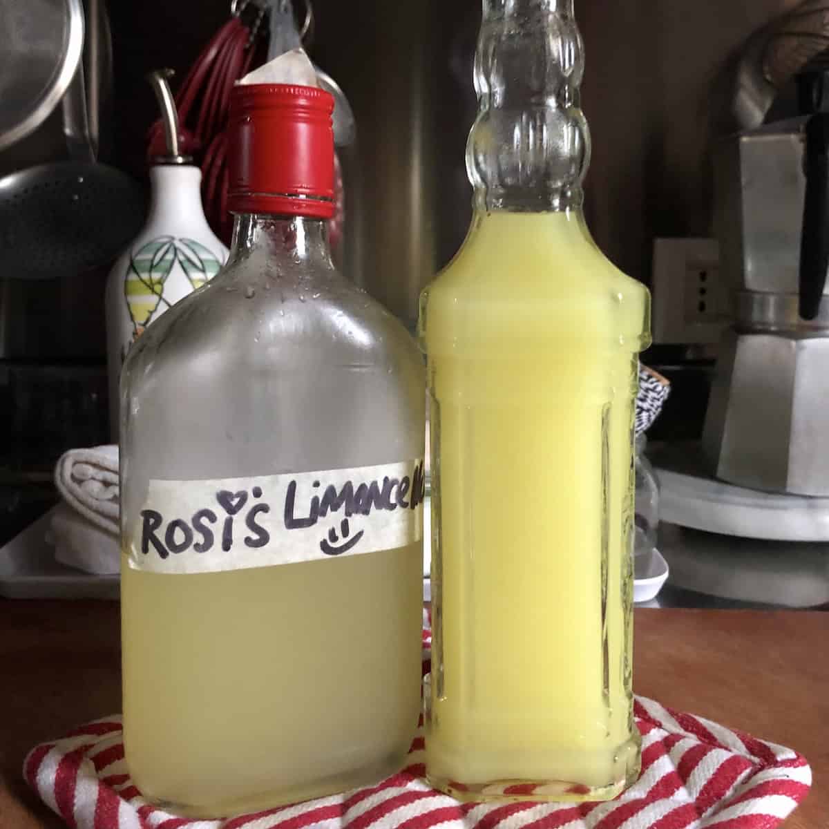 Rosi's cured homemade limoncello bottle next to my freshly made cloudy-looking limoncello showing the difference when you first combine the simple syrup versus after curing, making limoncello at home step by step.