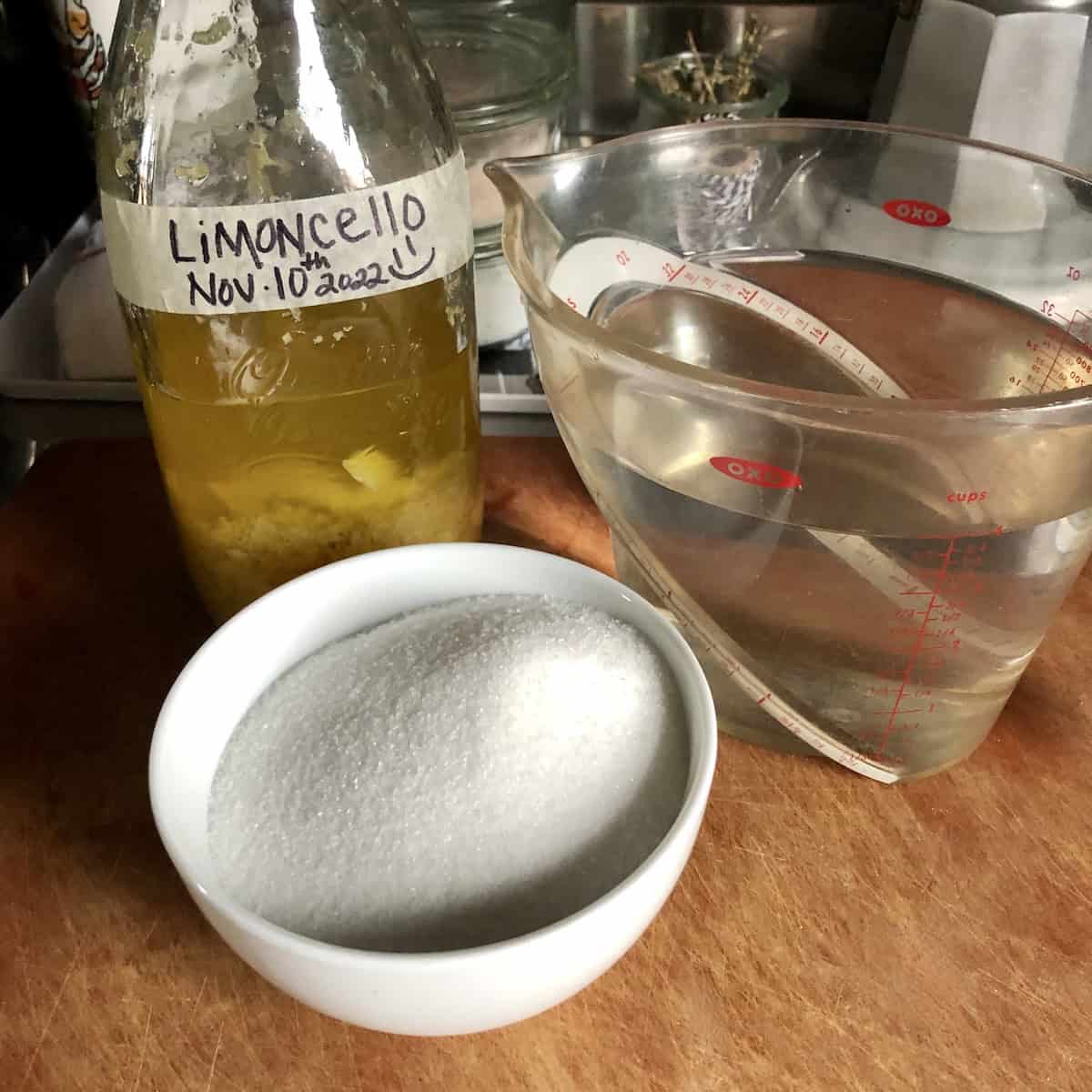 Sugar, water, and cured lemon zest in pure grain alcohol ready to combine to finish the limoncello, easy liquor recipes for how do you make limoncello with a simple syrup at home.
