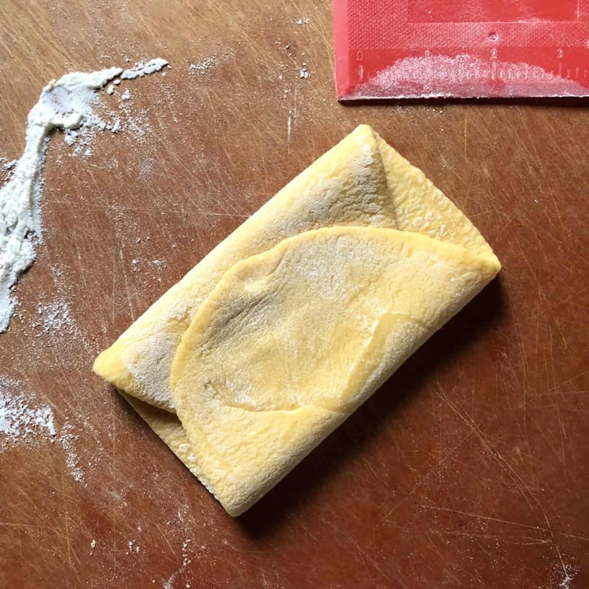 Semolina and 00 flour pasta dough folded like a business letter before rolling again on the widest setting to develop structure.
