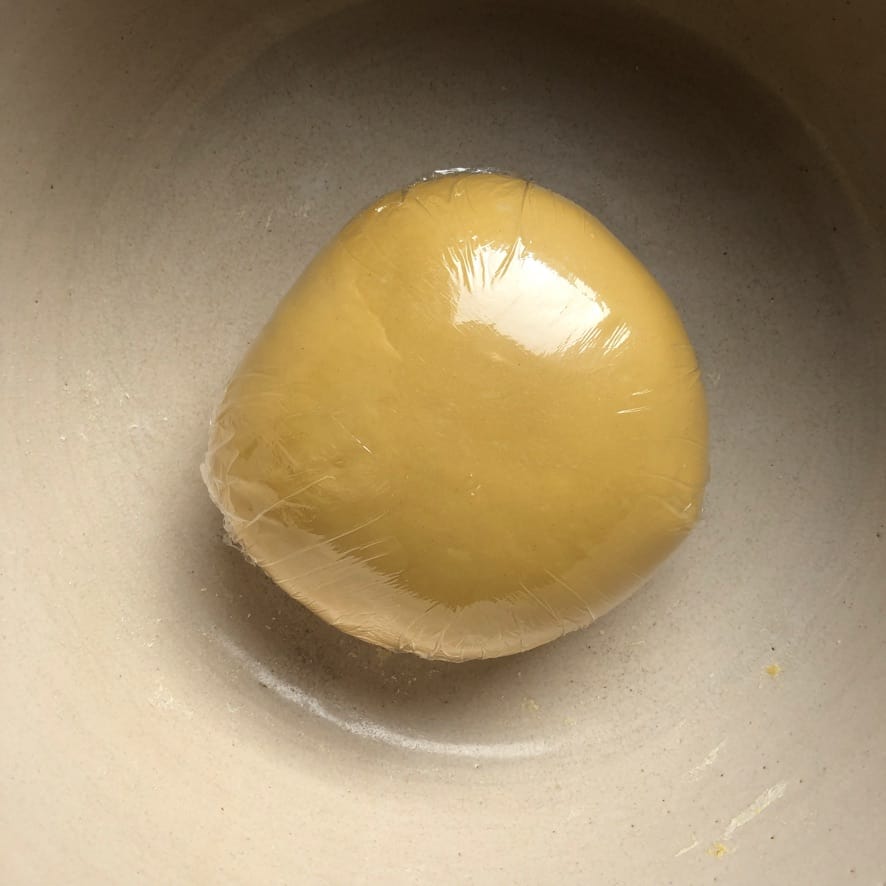 Kneaded egg pasta dough ball covered with sustainable cling film.