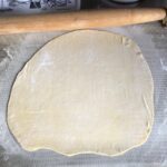one dough round rolled out thinly and ready to be cut