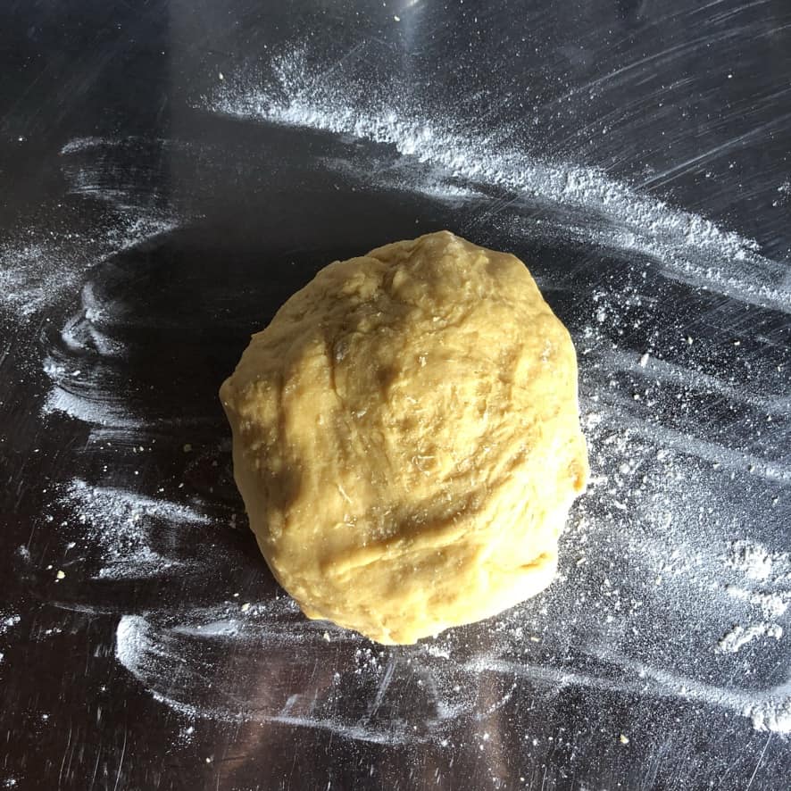dough round added to a very lightly floured stainless steel surface to be kneaded