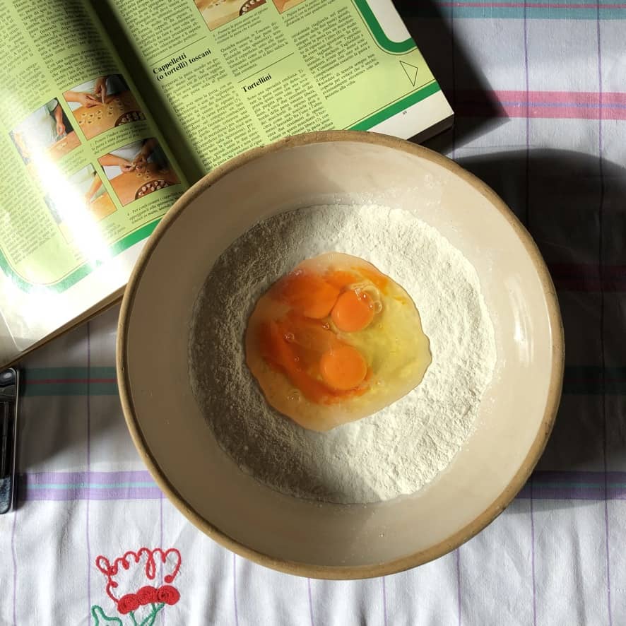 eggs cracked into the well of a flour mound in a mixing bowl