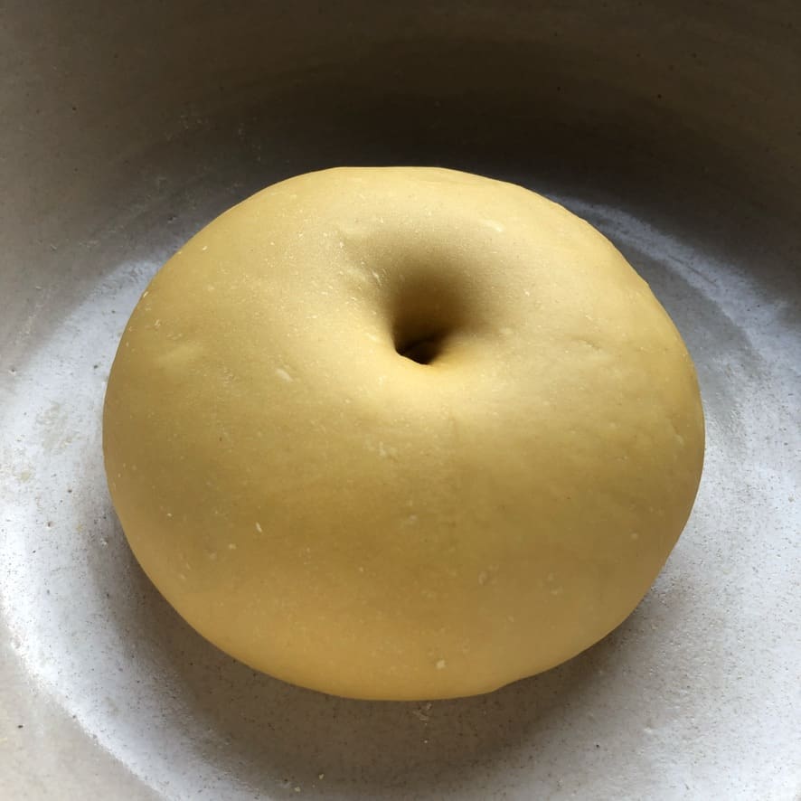 Egg pasta dough ready to be rolled after resting long enough showing how to tell when it's ready to roll by a hole poke into the center of dough remains when I remove my finger.