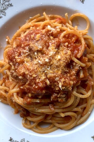 deep red spaghetti with beef ragù in a pasta bowl