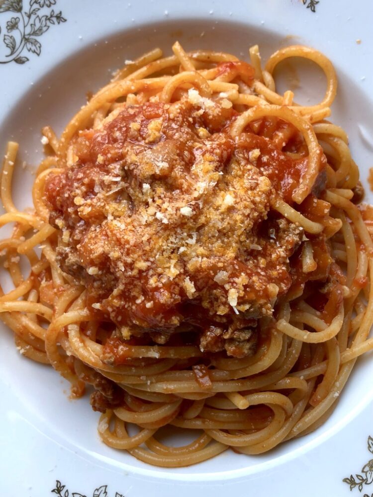 deep red spaghetti with beef ragù in a pasta bowl
