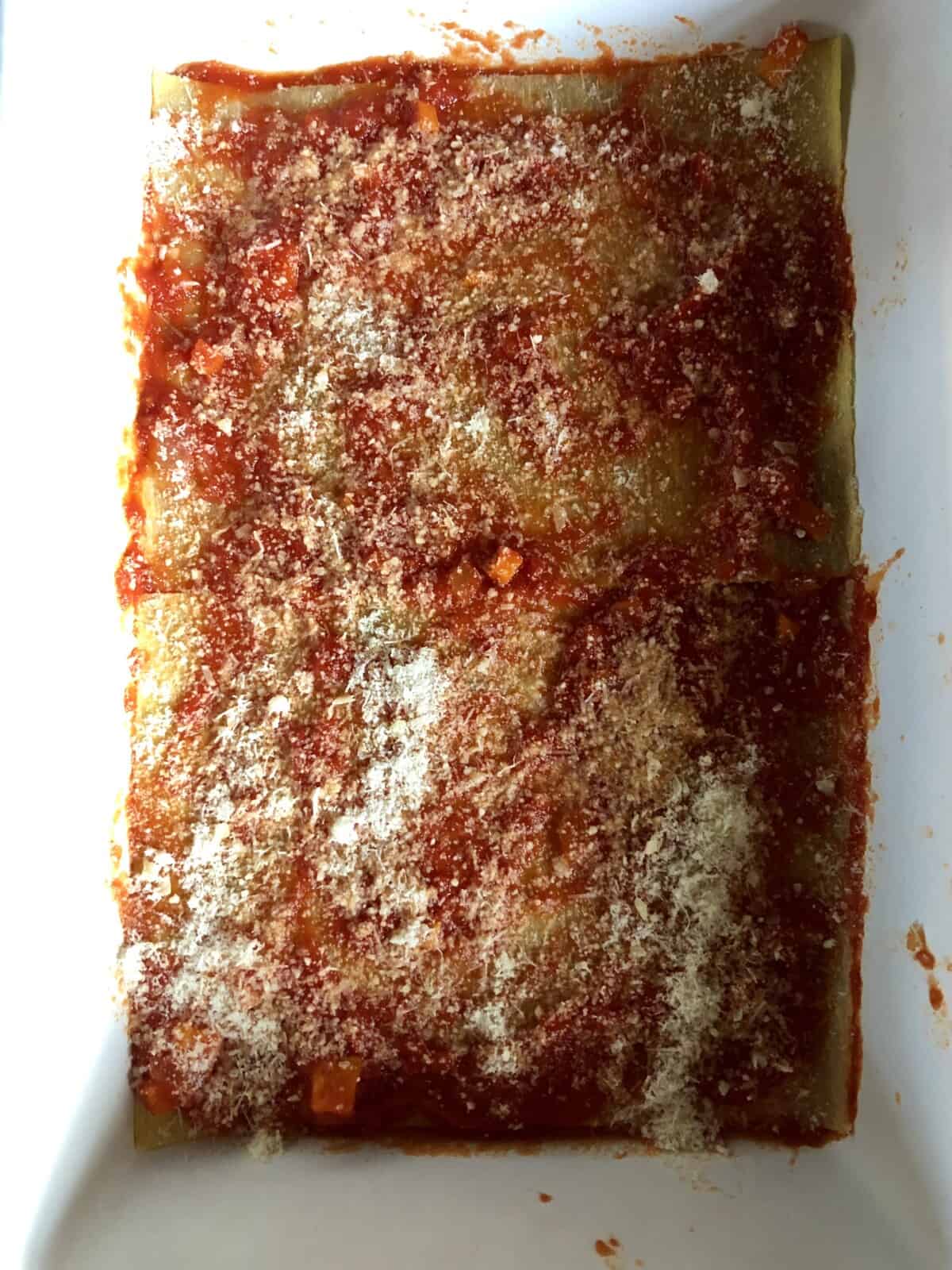 sauce and grana padano cheese sprinkled spread out and sprinkled on top of lasagna sheets