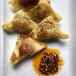 wonton wrappers filled and in a triangle shape and fried and steamed to make potstickers