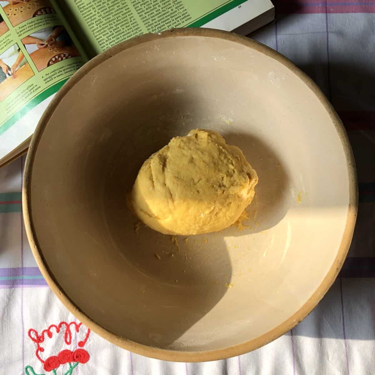 a shaggy ball of homemade egg pasta dough in a bread bowl