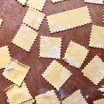 homemade egg pasta cut into zigzagged squares to fill with tortellini di Bolognese filling