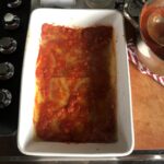 tomato sauce spread out thinly and evenly over the sheet of lasagna