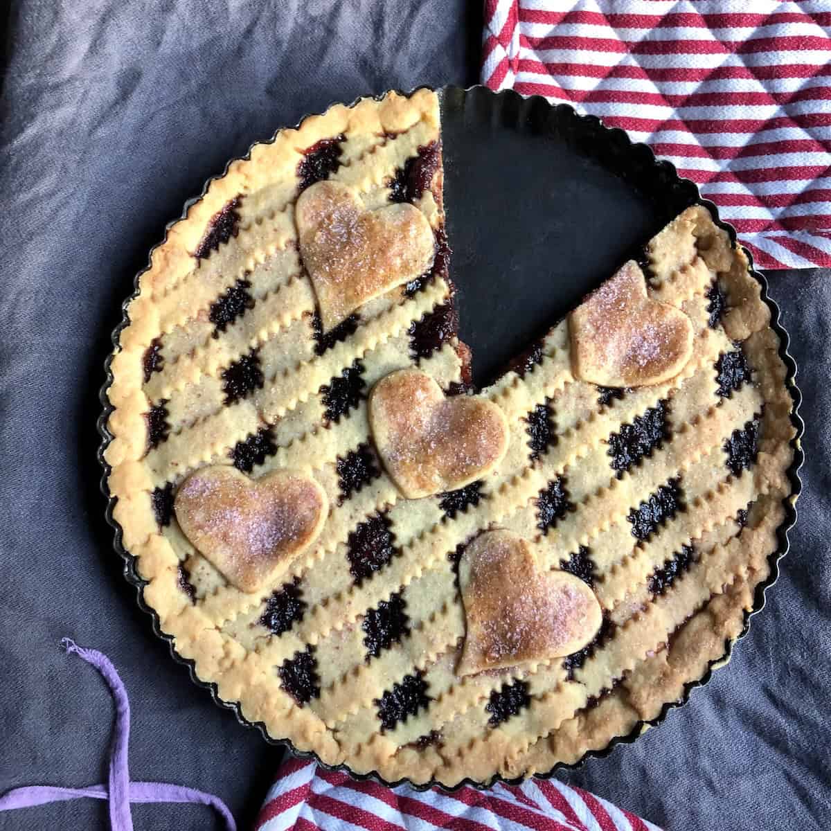 Homemade cherry crostata (crostata alla ciliegia) with two slices removed showing tender crumbly pasta frolla crust texture and glistening cherry jam filling, demonstrating what authentic Italian jam tart should look like when perfectly baked.