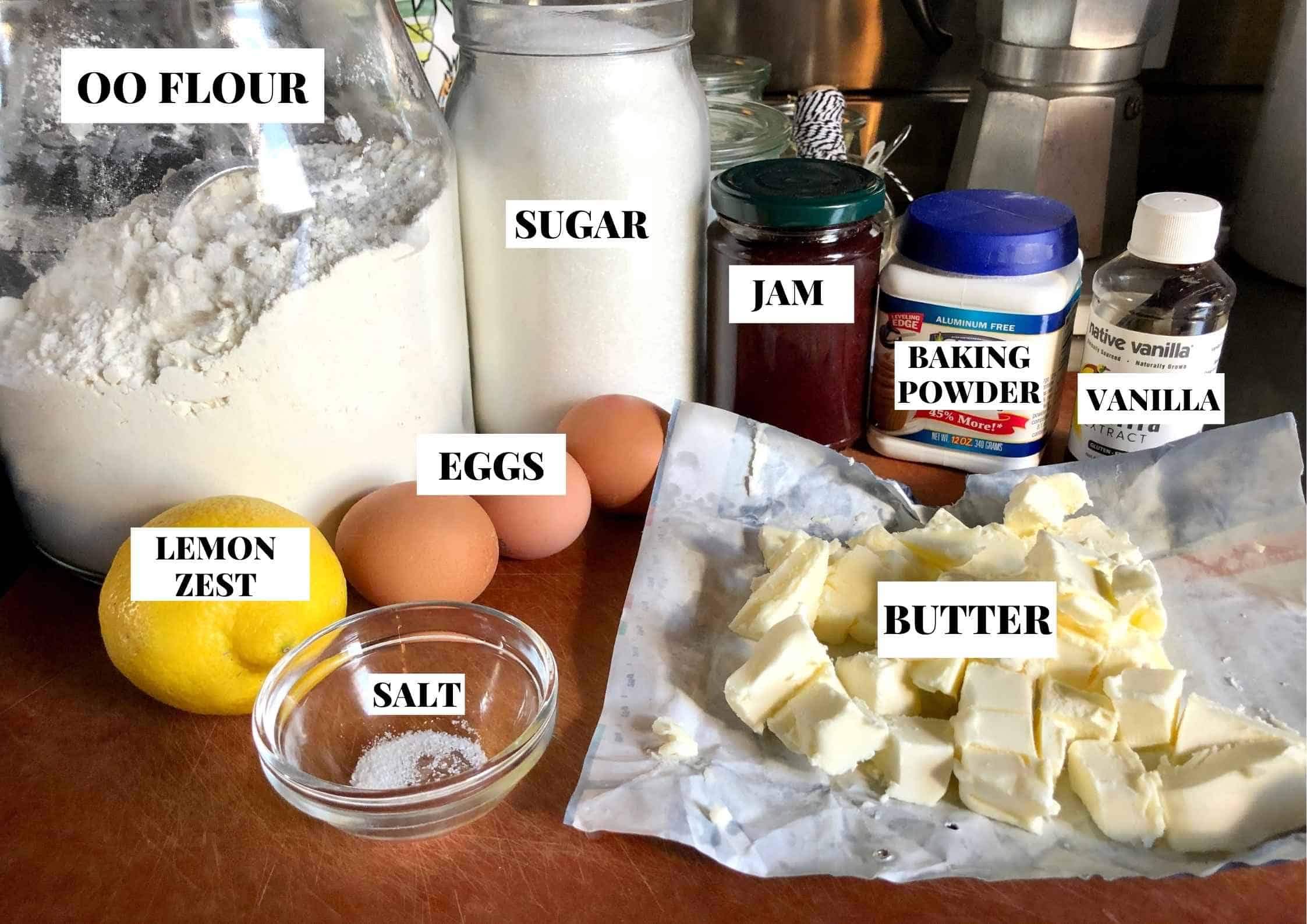 talian crostata ingredients labeled on a cutting board showing 00 flour, unsalted butter, sugar, eggs, egg yolks, baking powder, salt, vanilla extract, lemon zest, and jam for making authentic pasta frolla shortcrust pastry dough for crostata di marmellata.