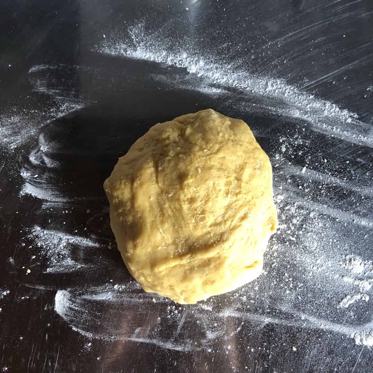 Semolina and 00 flour pasta dough ball on a lightly floured countertop ready to start kneading, half semolina half 00 flour pasta dough.