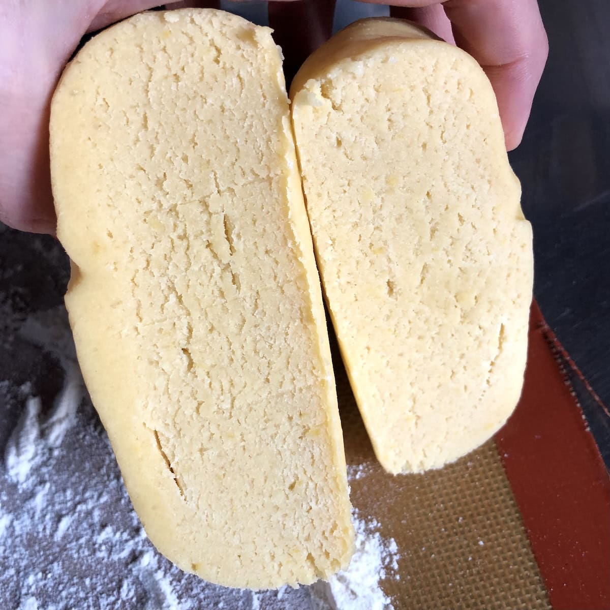 Chilled pasta frolla dough cut in half to portion for top and bottom crostata crusts, showing smooth interior texture of Italian shortcrust pastry ready to roll out for authentic crostata di marmellata, Italian jam tart, or fruit crostata recipes.