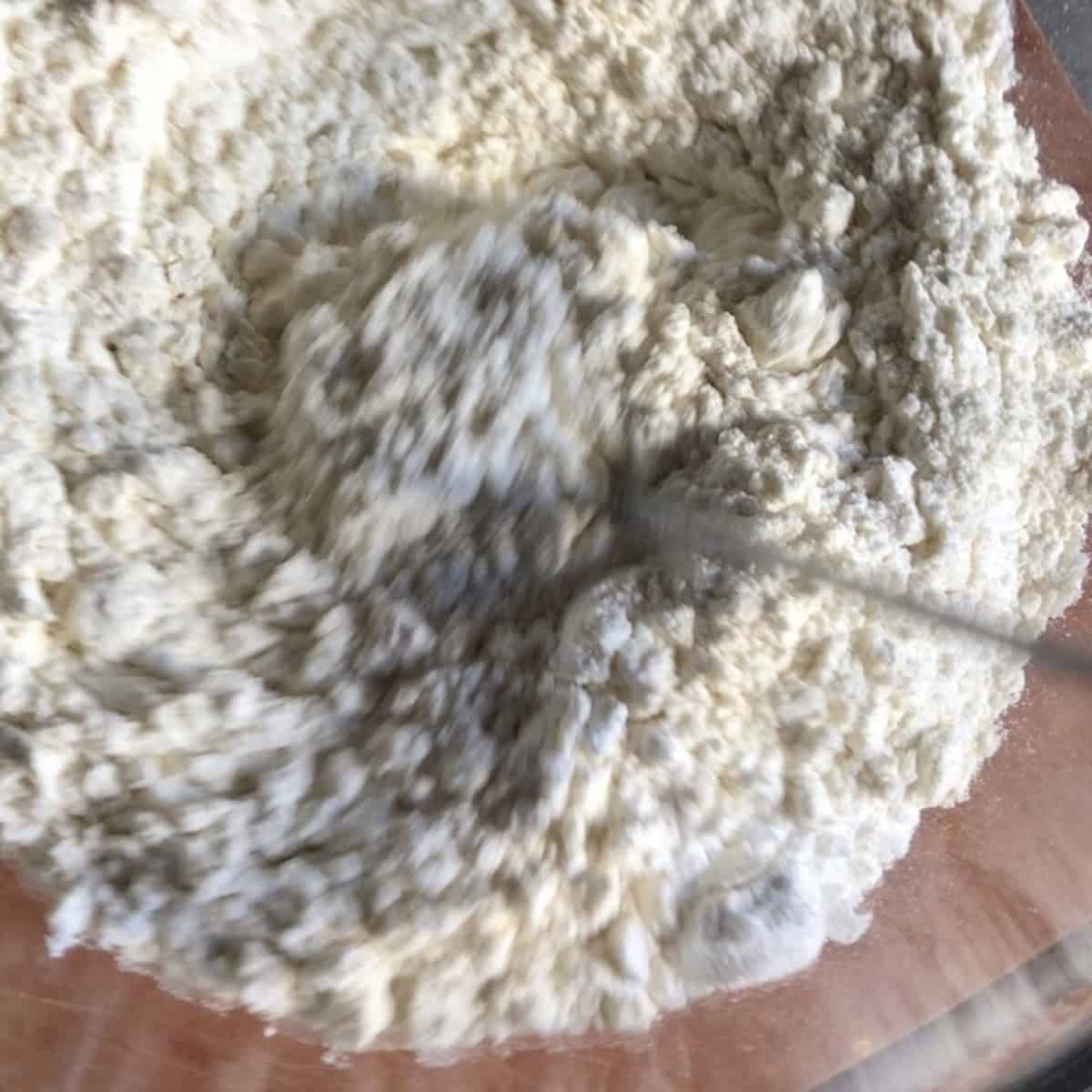 Dry ingredients for pasta frolla whisked together in bowl showing 00 flour, baking powder, and salt blended well before folding into wet ingredients for Italian crostata dough recipe.