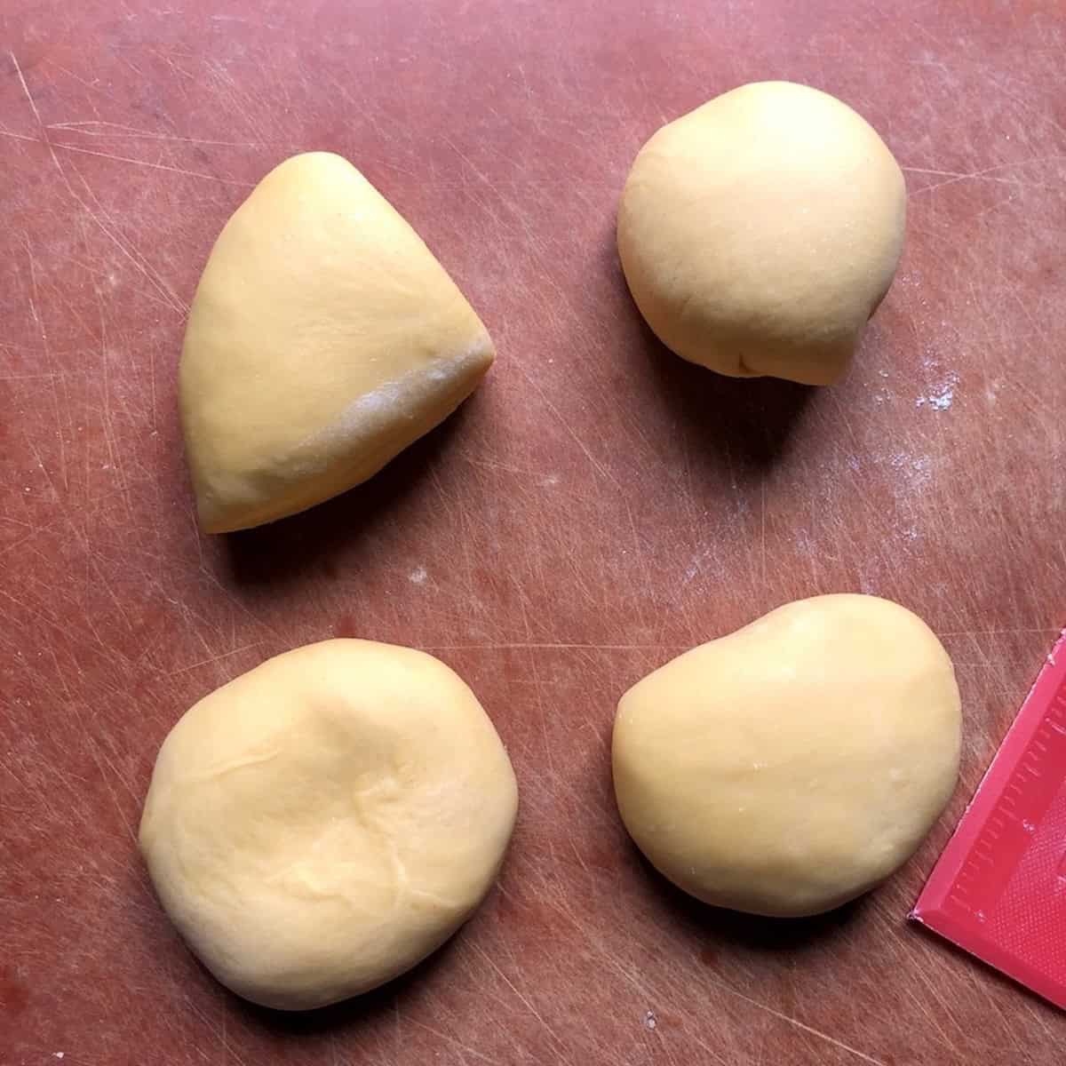 Semolina and 00 flour pasta dough divided into four equal pieces ready to roll, semolina and 00 flour pasta recipe portioning step.