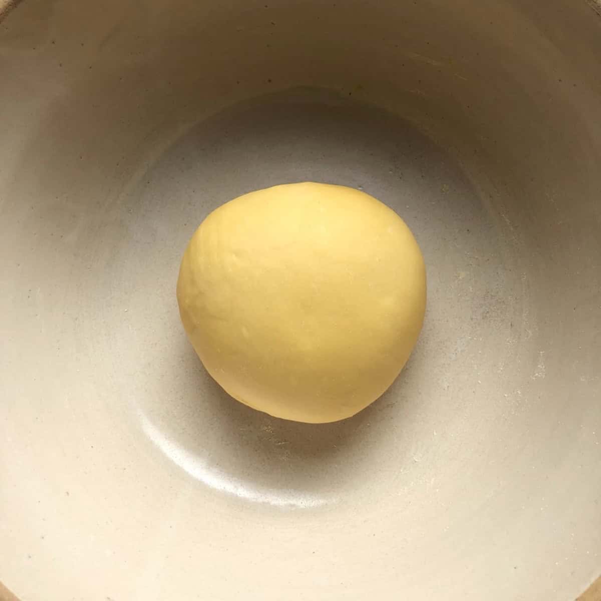 freshly kneaded semolina and 00 flour pasta dough ball with a smooth surface ready to rest before rolling, homemade pasta with 00 flour and semolina rimacinata.