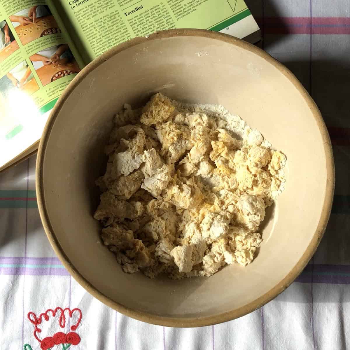 Shaggy semolina and 00 flour mixture with eggs combined but not yet formed into a dough round, homemade pasta with 00 flour and semolina before kneading.