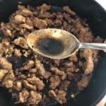adding the soy sauce to the skillet with the meat mixture