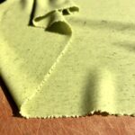 a beautiful sheet of green pasta dough that looks like ribbons of material, ready to be cut and shaped