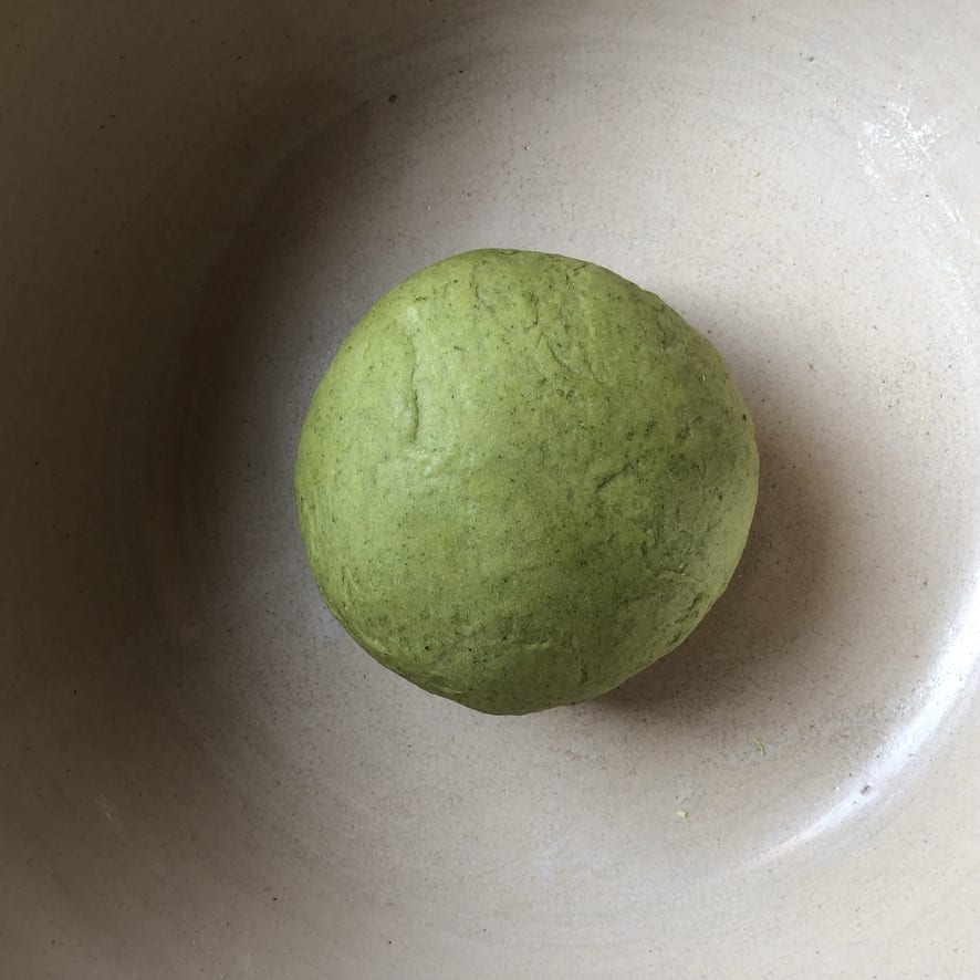 Spinach pasta dough ball after it's been rested for 2 hours looking hydrated and rich with a sheen to it
