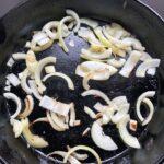 large sliced onions sautéing in a skillet