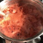 a super pink and foamy a thicker boiling strawberry jam mixture with the liquid noticeably reduced