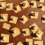 homemade egg pasta cut into zigzagged squares with little dots of tortellini filling on each square