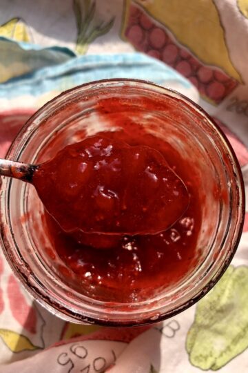 a spoon full of homemade strawberry jam being taken out of the widemouth mason Ball jar