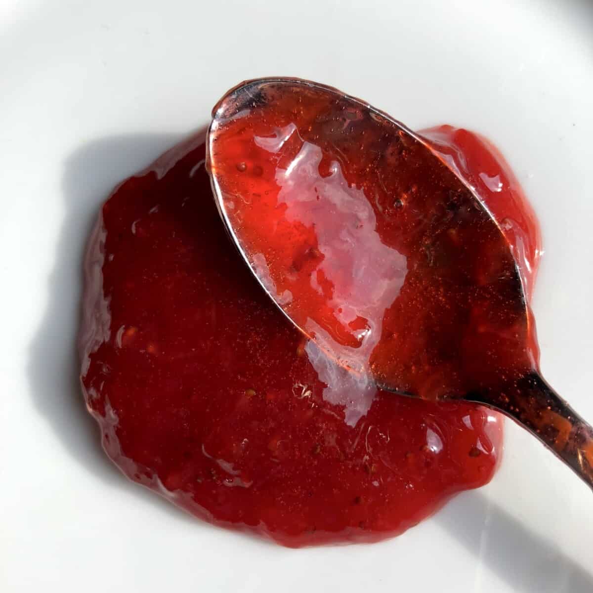 a spoon full of strawberry jam on a plate