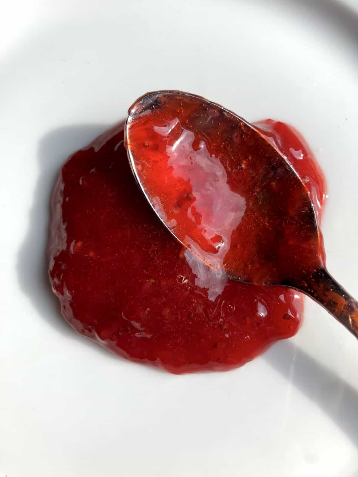 a spoon full of strawberry jam on a plate