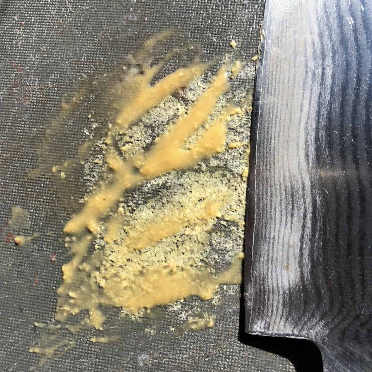 ginger turned into a paste using the back of a knife to scrape it on a cutting board