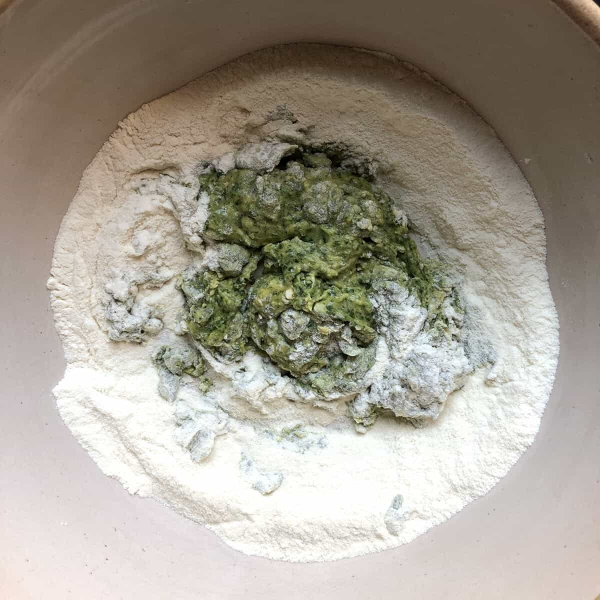 eggs, EVOO, and spinach in the well of a mound of semolina flour starting to come together