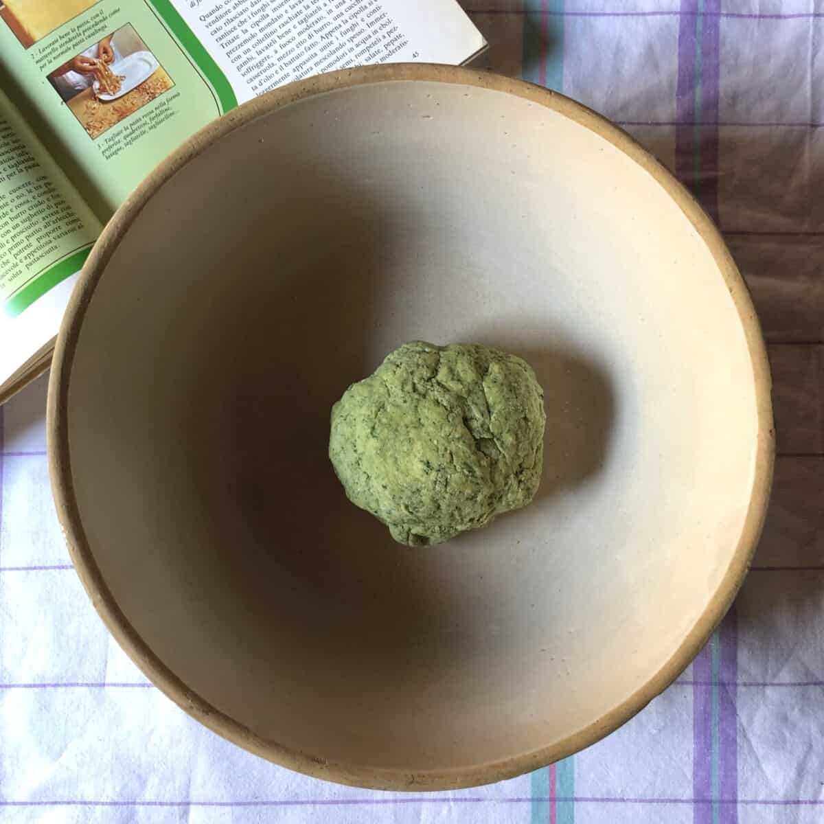 a very shaggy and rough looking green ball of spinach pasta dough just formed