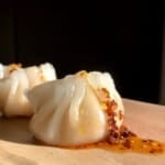 Homemade har gow crystal shrimp dumpling on a pink marble platter showing translucent dumpling skin with pink shrimp visible inside.