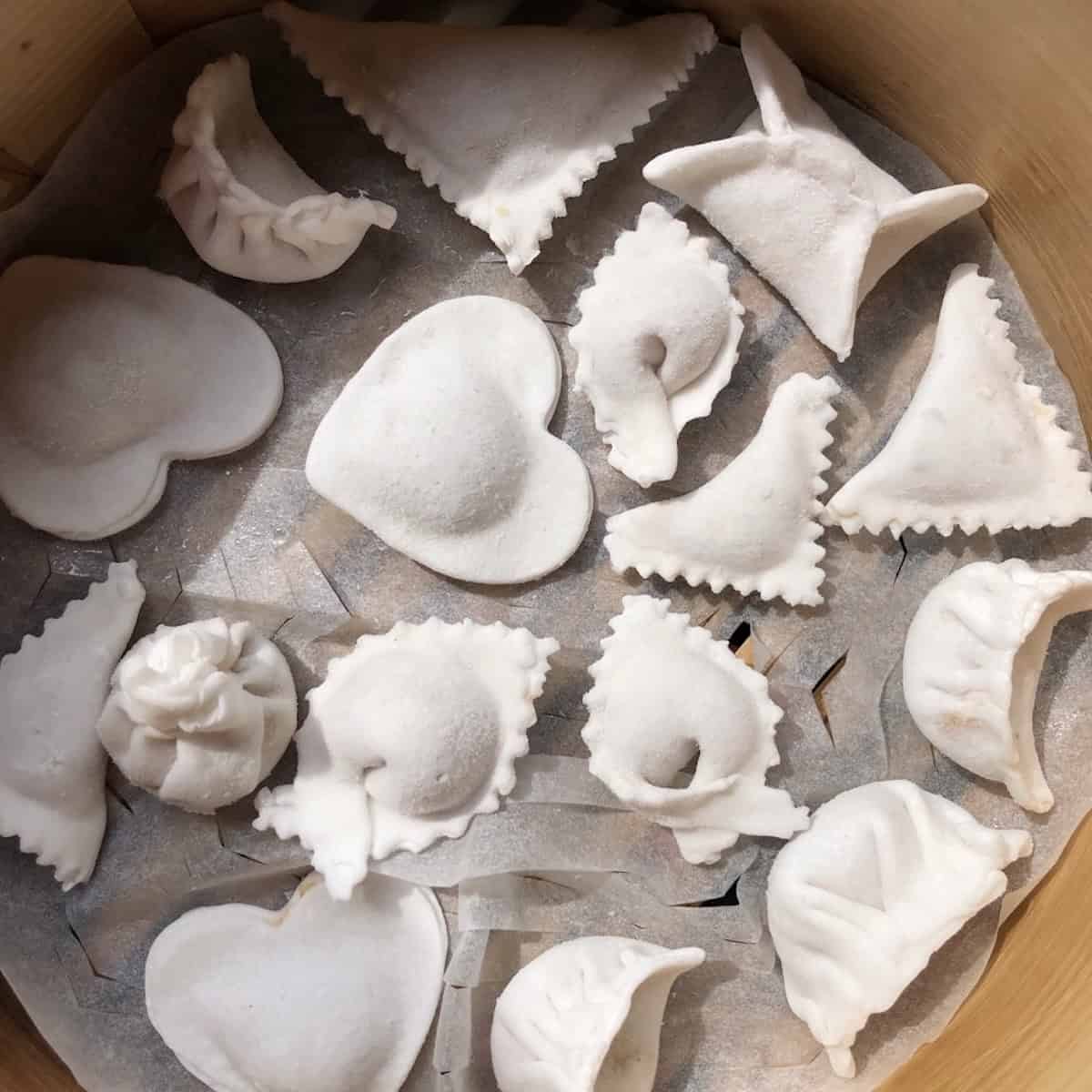 A plate of frozen uncooked har gow in a lined bamboo steamer showing how to make shrimp dumplings ahead and cook them from frozen. 
