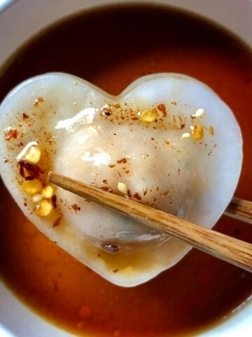 Homemade har gow crystal shrimp dumpling on a pink marble platter showing translucent dumpling skin with pink shrimp visible inside.