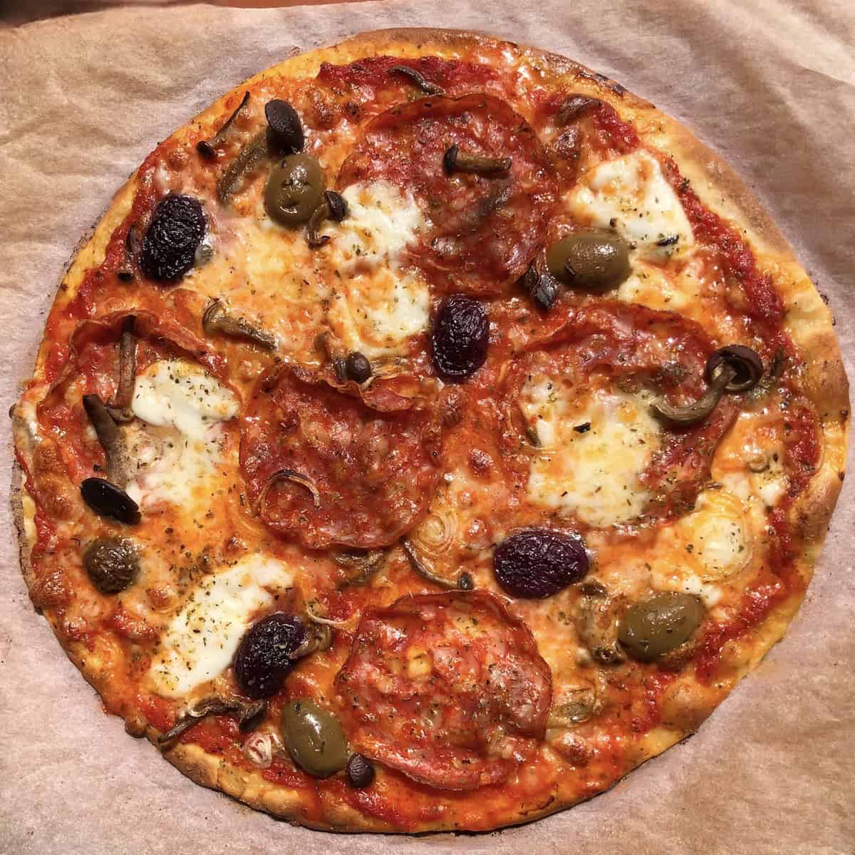 Homemade 00-thin crust pizza with pioppini mushrooms, pepperoni, shallots, mozzarella, buffalo mozzarella, and large green and black olives.