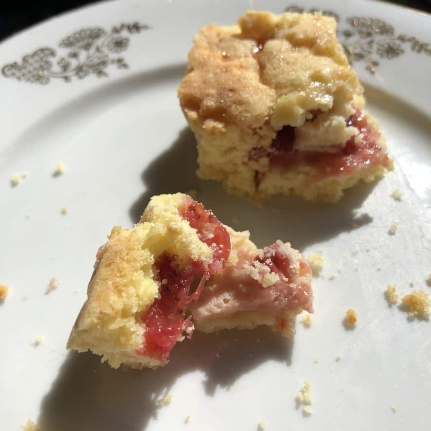 lattice-topped strawberry cheesecake crostata with homemade strawberry jam partially eaten revealing the contrasting bright red jam and pink strawberry cheesecake
