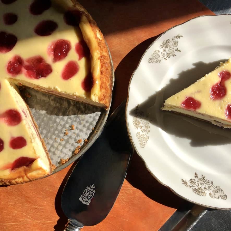 top down view of a slice of strawberry polka dotted cheesecake and the whole cheesecake with slice removed