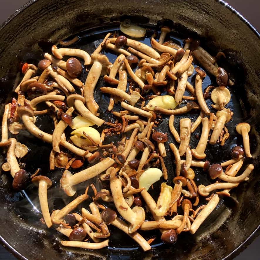 a cast iron skillet full of beautiful golden brown and perfectly seared pioppini black poplar mushrooms