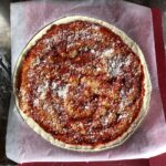 Homemade Pizza sauce spread out evenly across the pizza dough leaving a 1/2 inch border around the edges and sprinkled with grana padano cheese.