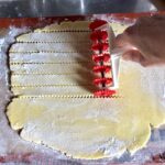 using a pasta bike to cut zigzagged lattice crust pieces to top the crostata