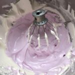 a mixing bowl filled with a layer of white marshmallow mixture and a lavender marshmallow mixture