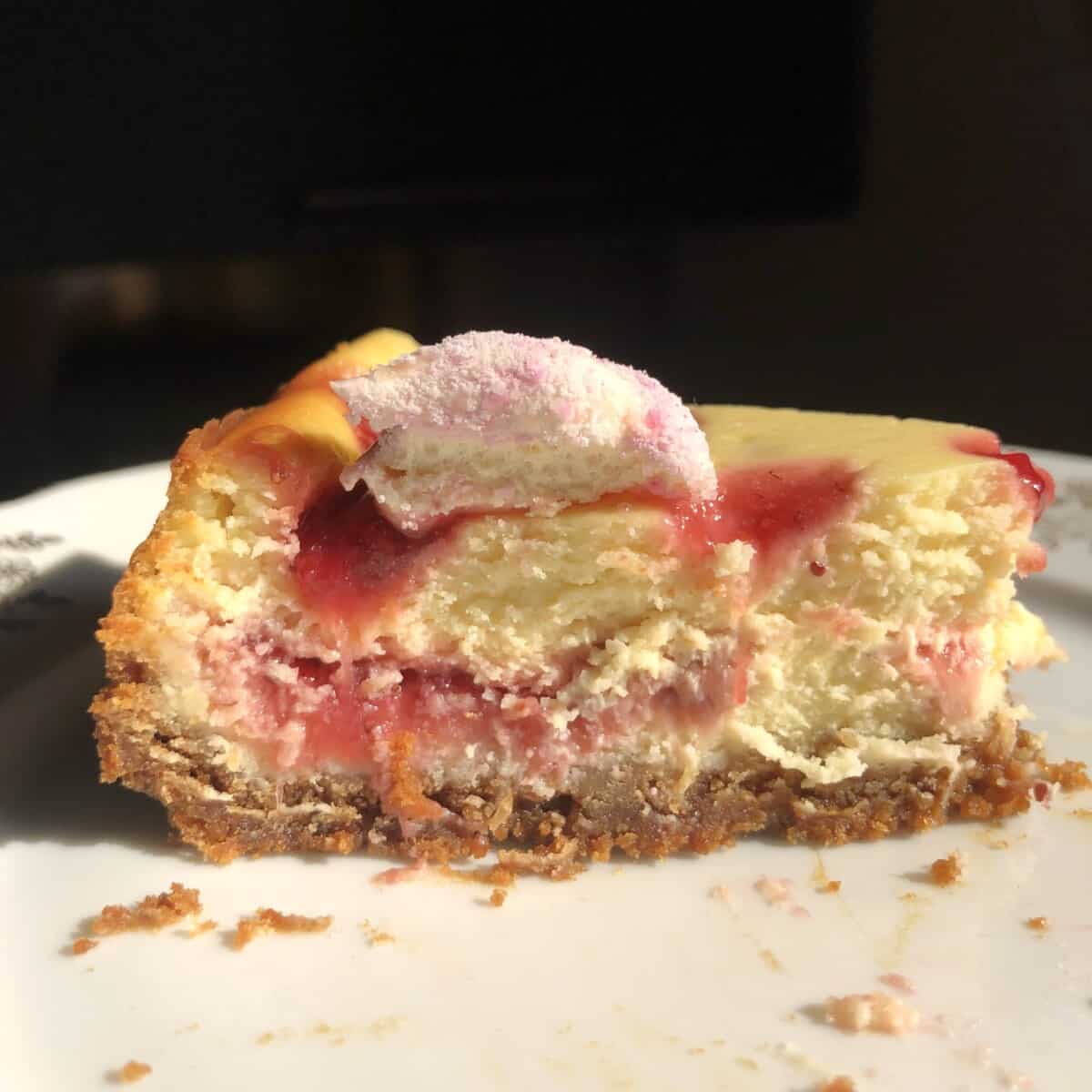 side view of strawberry cheesecake with a half eaten homemade strawberry peep on top