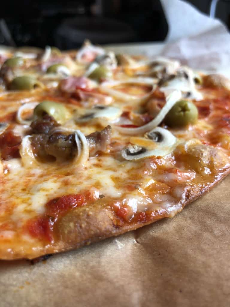 whole wheat Supreme pizza with green olives, spicy ventricina salami, salsiccia, prosciutto cotto, mushrooms, red bell peppers, and onions.
