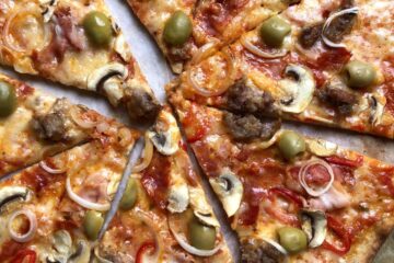 Super crispy sliced whole wheat Supreme pizza with green olives, spicy ventricina salami, salsiccia, prosciutto cotto, mushrooms, red bell peppers, and onions.