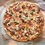 Super crispy sliced whole wheat Supreme pizza with green olives, spicy ventricina salami, salsiccia, prosciutto cotto, mushrooms, red bell peppers, and onions.